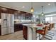 Gourmet kitchen featuring dark wood cabinetry, stainless steel appliances, and a large granite island with bar seating at 1158 Sugarloaf Ln, Erie, CO 80516