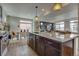 Granite kitchen island with pendant lights, dark cabinetry, and an open view into the dining and living area at 1158 Sugarloaf Ln, Erie, CO 80516