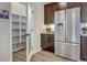 Walk-in pantry with ample shelving located next to stainless steel fridge and dark wood cabinets at 1158 Sugarloaf Ln, Erie, CO 80516