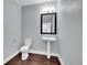 Clean bathroom features a pedestal sink, toilet, and framed mirror with modern lighting at 3612 Hudson St, Denver, CO 80207