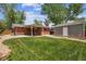 Expansive backyard features a lush lawn, brick house, covered patio, and detached garage for versatile outdoor enjoyment at 7192 W 67Th Pl, Arvada, CO 80003