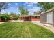 Lush lawn with a brick house and detached garage, perfect for outdoor gatherings and activities at 7192 W 67Th Pl, Arvada, CO 80003
