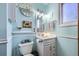 Bathroom with a pastel blue tone, featuring a vanity, toilet, mirror, and decorative clock at 3680 S Gibralter Cir, Aurora, CO 80013