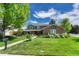 Inviting two-story home boasts a lush lawn, mature tree, and a charming brick and gray exterior at 10289 E Berry Dr, Greenwood Village, CO 80111