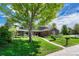 Beautifully landscaped front yard of a brick home with mature tree and paved walkway at 10289 E Berry Dr, Greenwood Village, CO 80111
