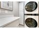 Modern laundry room with white cabinetry, a quartz countertop, and a stacked washer and dryer at 10289 E Berry Dr, Greenwood Village, CO 80111