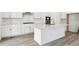 Modern kitchen with island, white cabinets, stainless hood and gas cooktop at 9266 Telluride Ct, Commerce City, CO 80022