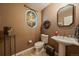 Stylish powder room with designer wallpaper, oval window, decorative mirror, and pedestal sink at 4545 S Monaco St # 243, Denver, CO 80237