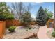 Landscaped backyard features decorative rock ground cover, mature trees, and a wooden fence at 11460 W Tanforan Cir, Littleton, CO 80127