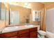 Bathroom with double sinks, cherry wood vanity, framed mirror, and shower with tan shower curtain at 11460 W Tanforan Cir, Littleton, CO 80127