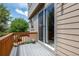 Back deck featuring wood railing, sliding glass door, and views of lush landscaping at 11460 W Tanforan Cir, Littleton, CO 80127