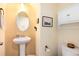 A clean half-bathroom featuring a pedestal sink, oval mirror, and convenient toilet paper holder at 11460 W Tanforan Cir, Littleton, CO 80127