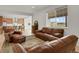 Bright living room featuring light wood floors, leather furniture, and a large window with neighborhood views at 7325 S Waterloo Way, Aurora, CO 80016