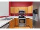 Kitchen featuring wood cabinets, stainless steel appliances, and a breakfast bar with white countertop at 8707 E Florida Ave # 614, Denver, CO 80247