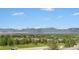 Expansive view overlooking rooftops and lush greenery with a stunning mountain range in the distance on a clear day at 1425 Blue Sky Cir # 15-301, Erie, CO 80516