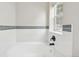 Bathtub with white tile surround, black fixtures and a window to exterior at 8773 S Dudley St, Littleton, CO 80128