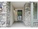 Close-up of the front entrance, with stonework, a secure door, and stylish outdoor lighting at 8773 S Dudley St, Littleton, CO 80128