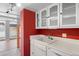 Kitchen sink with a view to the balcony, white cabinets, and bright red walls at 1250 N Humboldt St # 202, Denver, CO 80218