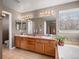 Bathroom with dual sinks, a large mirror, and an integrated bathtub at 11910 W 83Rd Pl, Arvada, CO 80005