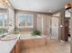 Well-lit bathroom features a soaking tub, walk-in shower with glass enclosure, and a large window at 11910 W 83Rd Pl, Arvada, CO 80005