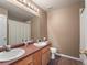 Classic bathroom with dual sinks, a large mirror, and neutral earth tones at 11910 W 83Rd Pl, Arvada, CO 80005