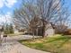 Scenic front yard with mature trees and a spacious driveway leading to a two-car garage at 11910 W 83Rd Pl, Arvada, CO 80005