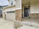 Charming front porch with stone accents, black front door, and three-car garage at 11657 Olathe St, Commerce City, CO 80022