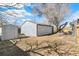 View of the detached garage and shed in the backyard, offering ample storage, set against a mature shade tree at 315 S Xapary St, Aurora, CO 80012