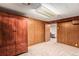 Finished basement area with built-in wood armoire, wood paneled walls and neutral carpeting at 3225 W Mexico Ave, Denver, CO 80219