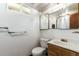 Modest bathroom with wood vanity, basic fixtures, and natural light from a window at 3225 W Mexico Ave, Denver, CO 80219