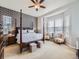 Elegant main bedroom with a four-poster bed, patterned accent wall, and cozy sitting area at 424 N De Gaulle Ct, Aurora, CO 80018