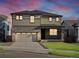 Two-story home with a stone facade, gray siding, and well-maintained lawn at sunset at 6156 Hourglass Dr, Brighton, CO 80601