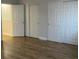 Bright bedroom with wood-look flooring featuring three closets with white doors, offering plenty of storage at 4580 W Alameda Ave, Denver, CO 80219