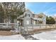 View of gray siding townhome exterior with a snow covered yard and low brick wall and white wooden fence at 912 S Yampa St # 208, Aurora, CO 80017