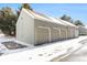 Row of individual garages with gray siding and light brown doors in a snowy setting at 912 S Yampa St # 208, Aurora, CO 80017