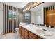 Bathroom features dual sinks, large mirror, black-and-white striped wallpaper, and a window with natural light at 8095 Garrison Ct # B, Arvada, CO 80005