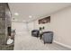 Cozy basement with neutral walls and gray upholstered chairs is brightly lit with recessed lights at 7604 Reed St, Arvada, CO 80003