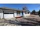 Charming single-story home with a blue front door, white brick, attached garage, and landscaped yard at 7604 Reed St, Arvada, CO 80003