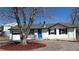 Charming brick home with a blue front door, and landscaping at 7604 Reed St, Arvada, CO 80003