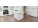 Kitchen island with white quartz countertop and light brown wood flooring at 1224 Sugarloaf Ln, Erie, CO 80516