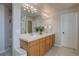 Well-lit bathroom with double sinks, wooden cabinetry, tile floors, and ample counter space at 11918 S Hitching Post Trl, Parker, CO 80134