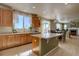 Open kitchen with island, wood cabinets, stainless dishwasher, and view into dining and living areas at 11918 S Hitching Post Trl, Parker, CO 80134