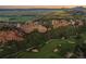 Sweeping aerial shot showcases the lush green golf course and rocky terrain surrounding the property at 6402 Wauconda Dr, Larkspur, CO 80118