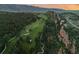 Panoramic aerial showcases a vibrant green golf course with rugged rock formations, and luxury homes at 6402 Wauconda Dr, Larkspur, CO 80118
