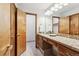 Bathroom features wood cabinets, a stone countertop, and a large mirror with vanity lighting at 2 Larkdale Dr, Littleton, CO 80123
