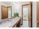 Bathroom with wood cabinets, stone countertops, and an open doorway to the shower area at 2 Larkdale Dr, Littleton, CO 80123
