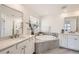 Serene bathroom featuring dual vanities, a soaking tub, and a large window for natural light at 5983 Fulton St, Denver, CO 80238