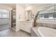 Bathroom with neutral decor featuring a soaking tub, separate shower, and natural light from the window at 5983 Fulton St, Denver, CO 80238