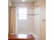 Bright bathroom with white tiled shower-tub, tan walls, and a window for natural light at 6378 Noble Ct, Arvada, CO 80403