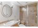 Bathroom featuring a glass enclosed shower, vanity with an oval mirror, and neutral colored tile at 10200 Julian St, Westminster, CO 80031